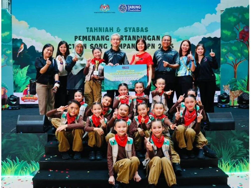 Anesee (lima dari kanan) menyampaikan replika kad berjumlah RM3,750 kepada Juara Pertandingan Action Song Peringkat Kebangsaan 2025.