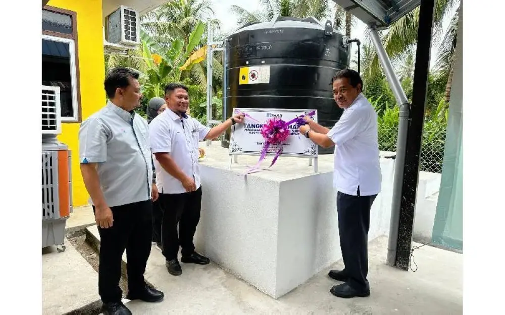 Jaseni (kanan) menggunting riben sebagai simbolik penyerahan tangki air kepada penduduk Kampung Lubok Simpul.