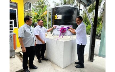 Jaseni (kanan) menggunting riben sebagai simbolik penyerahan tangki air kepada penduduk Kampung Lubok Simpul.