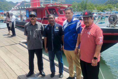 Dari kiri: Romli dan Zuraidi bergambar di hadapan ambulan air yang dilancarkan pada Ahad. Foto: Ihsan pembaca