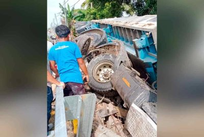 Keadaan treler terbalik selepas terlibat kemalangan dengan enam kenderaan di hadapan Masjid Sabak Uni, Jalan Kluang - Batu Pahat pagi Selasa.