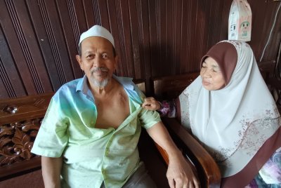 Meriam (kanan) menunjukkan kesan parut implan perentak jantung yang dipasang suaminya ketika ditemui di kediaman mereka di Kampung Hulu Takir, Kuala Nerus, Terengganu.