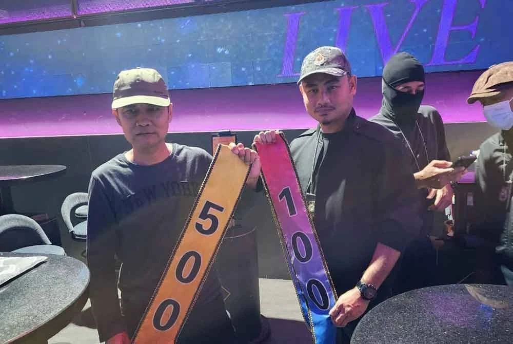 Wan Mohammed Saupee (kiri) menunjukkan kalungan disyaki tip yang akan dipakai oleh gadis pelayan di sebuah pub di Sri Hartamas, Kuala Lumpur.