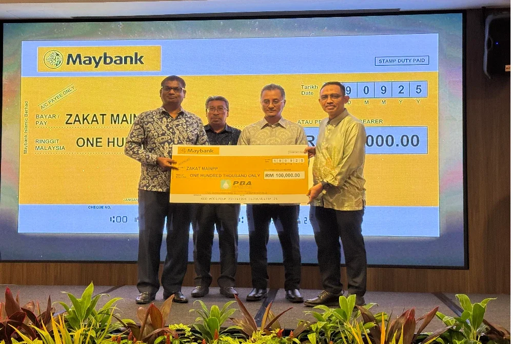 Pathmanathan (kiri) menyerahkan cek cura bernilai RM100,000 kepada Zakat MAINPP sambil disaksikan Mohamad (dua dari kanan) pada Majlis Penyerahan Zakat Perniagaan PBAPP Sdn Bhd pada Khamis.
