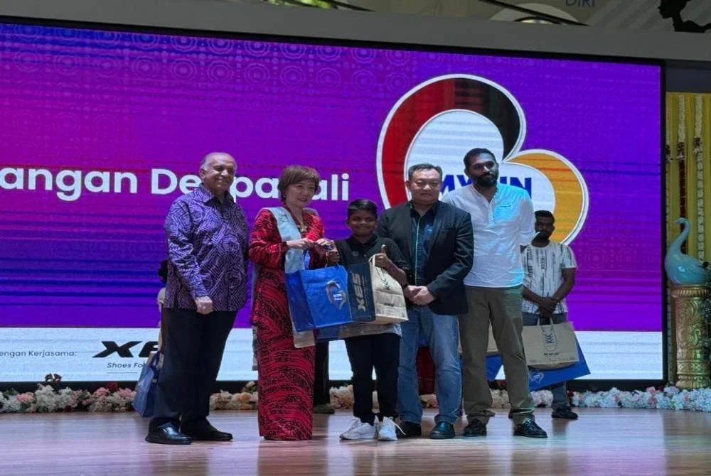 Ameer (kiri) dan Nicole (dua dari kiri) menyampaikan pakaian baharu kepada penerima kanak-kanak.