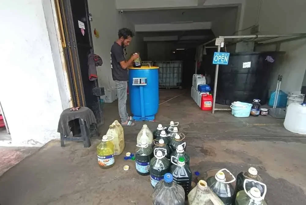 Mohd Lokman menapis semula minyak masak terpakai yang dihantar pelanggan di pusat pengumpulan minyak masak terpakai di Kuala Ibai, Kuala Terengganu.