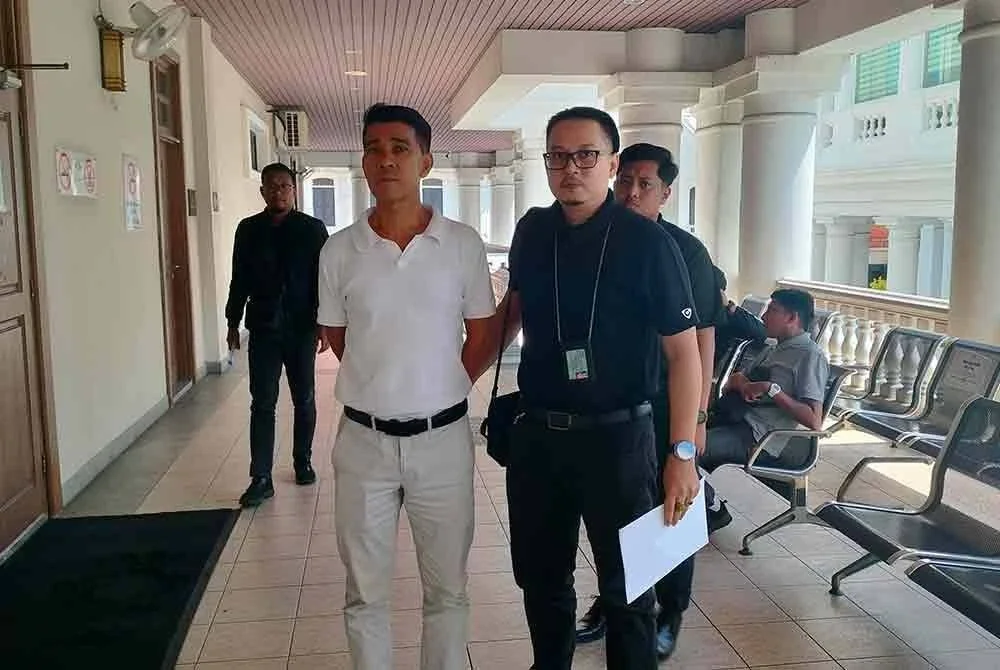 Cheng Tiam diiringi pegawai JPN ketika dibawa ke mahkamah pada Jumaat.