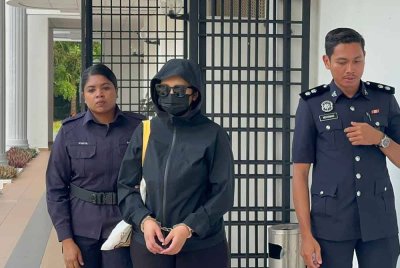 Tertuduh diiringi anggota polis ketika dibawa ke Mahkamah Balik Pulau pada Jumaat.