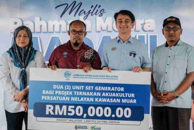 Muhammad Faiz (dua, kanan) menyampaikan replika cek bantuan sebanyak RM50,000 kepada Pengerusi Persatuan Nelayan Kawasan (PNK) Muar, Mohd Nur Hakim Simon (dua, kiri) pada Majlis Ramah Mesra Madani bersama Nelayan Muar pada Jumaat. Foto Bernama