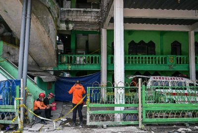 Anggota pasukan mencari dan menyelamat berehat seketika sementara operasi menyelamat diteruskan di tapak bangunan yang runtuh di Sekolah Pondok Islam Al Khoziny di Sidoarjo, Jawa Timur. Foto AFP