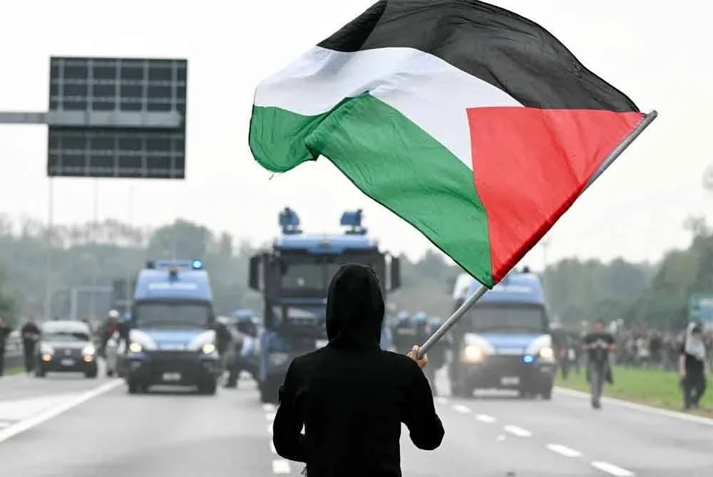 Seorang penunjuk perasaan pro-Palestin dilihat mengibarkan bendera Palestin di hadapan pasukan polis semasa protes yang berlangsung di lebuhraya Milan. Foto AFP