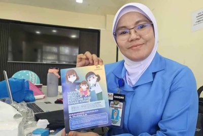 Radziah menunjukkan risalah program vaksin Measles dan Rubella percuma bagi kanak-kanak yang dijalankan sempena Jualan Gudang Karangkraf 2025.