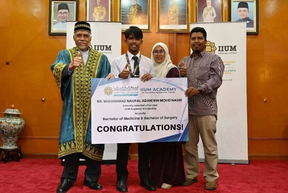 Osman (kiri) bersama Muhammad Naufal Adam dan kedua ibu bapa pelajar itu pada majlis penyerahan biasiswa di UIAM Gombak.