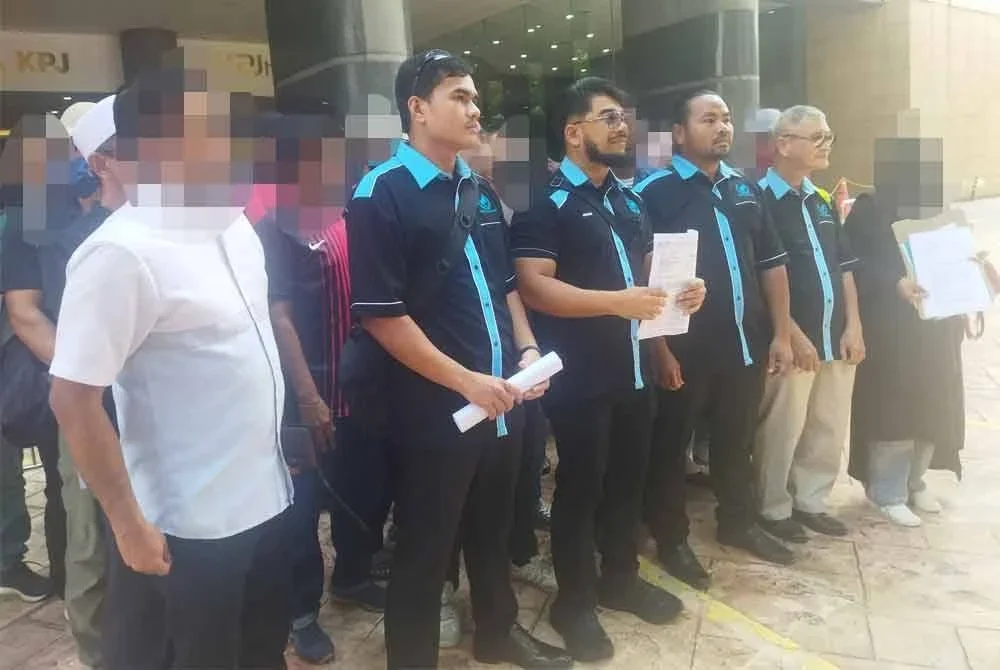 Hishamuddin (depan, tiga dari kiri) bersama mangsa penipuan pelaburan di hadapan pejabat Jabatan Siasatan Jenayah Komersial Bukit Aman, Kuala Lumpur pada Isnin.