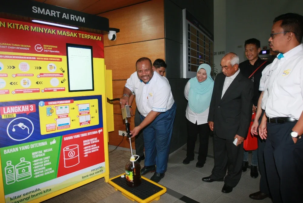 Ramli (kiri) menunjukkan cara mengitar semula minyak masak terpakai menggunakan RVM di Shah Alam pada Isnin.