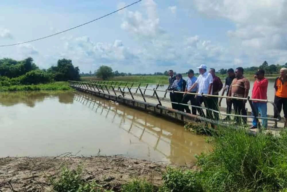 Dr Ismail (tengah) melihat keadaan Sungai Padang Kerbau semasa meninjau kawasan Wilayah III Pendang yang terjejas akibat banjir sejak Jumaat lalu.