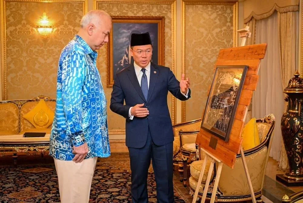 Kor Ming mempersembahkan cenderahati istimewa yang dihasilkan menggunakan bahan kitar semula oleh pelukis tempatan daripada SWCorp kepada Sultan Nazrin pada Jumaat. Foto KPKT