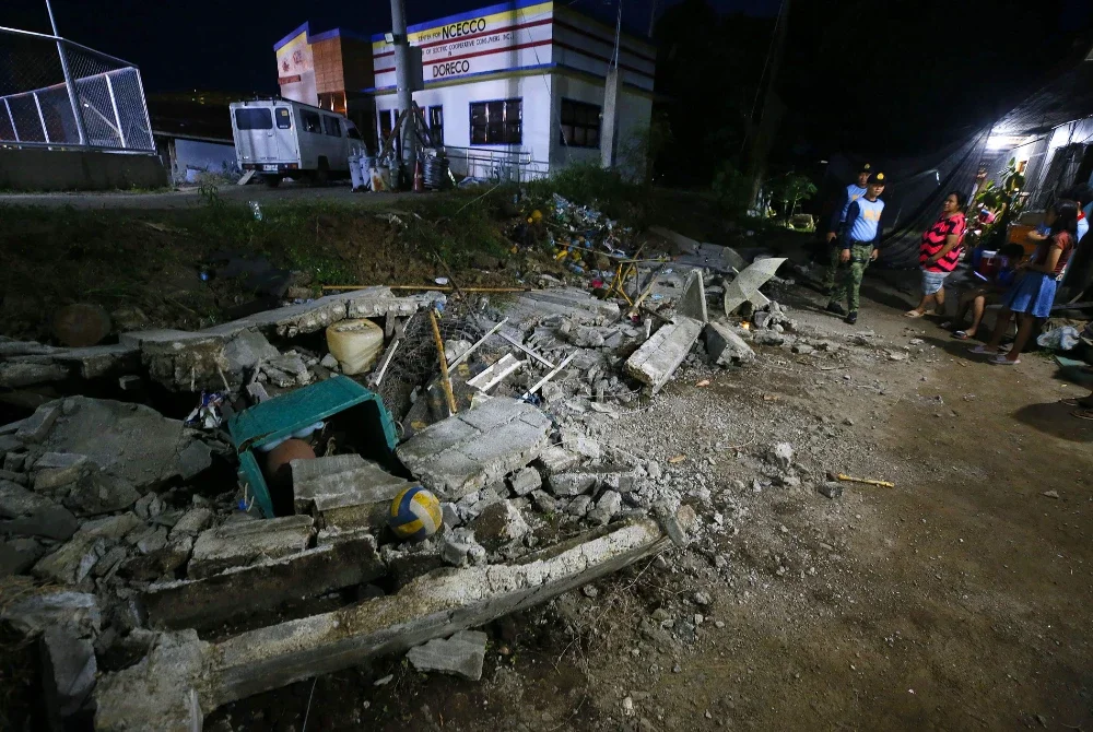 Polis berdiri di sebelah runtuhan dinding yang telah roboh di bandar Mati, wilayah Davao Oriental, di pulau selatan Mindanao, selepas gempa bumi bermagnitud 7.4 melanda wilayah tersebut. Foto AFP