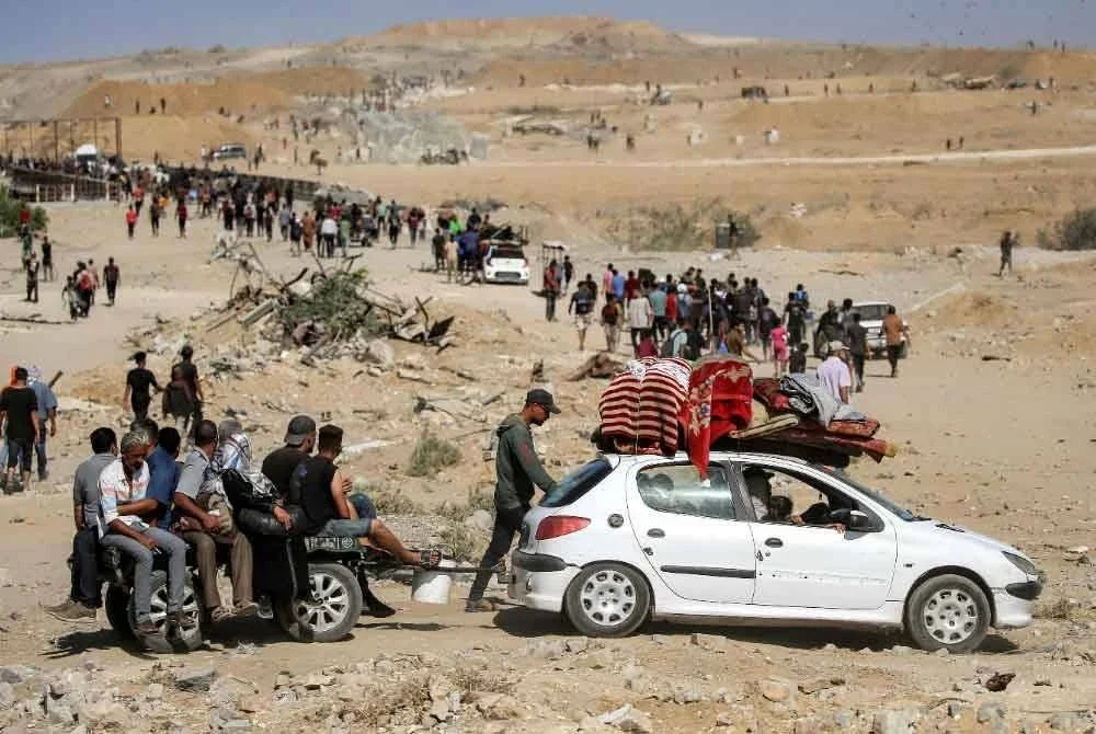 Orang ramai melalui kawasan yang dikenali sebagai 'koridor Netzarim' berhampiran Nuseirat di tengah Semenanjung Gaza pada 10 Oktober, dalam perjalanan pulang ke Bandar Gaza. Foto AFP