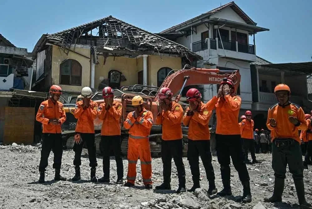 Anggota pasukan BASARNAS berdoa selepas majlis menandakan tamatnya operasi mencari dan pembersihan runtuhan sekolah pondok Al Khoziny di Sidoarjo, Jawa Timur. - AFP