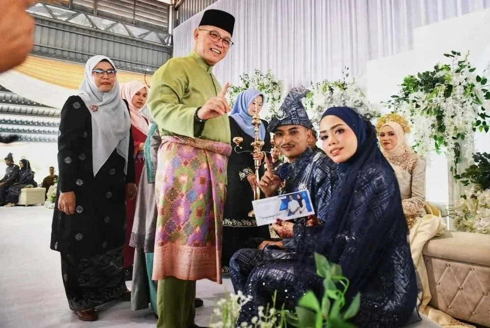 Wan Rosdy (dua dari kiri) menyampaikan sumbangan IMPahang kepada pengantin terlibat. Foto FB Wan Rosdy