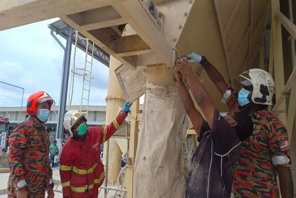 Anggota bomba membantu mengeluarkan mangsa yang tersepit di dalam mesin pengisar pasir di sebuah kilang di Kawasan Perindustrian Batu Gajah 3 di sini pada Ahad.