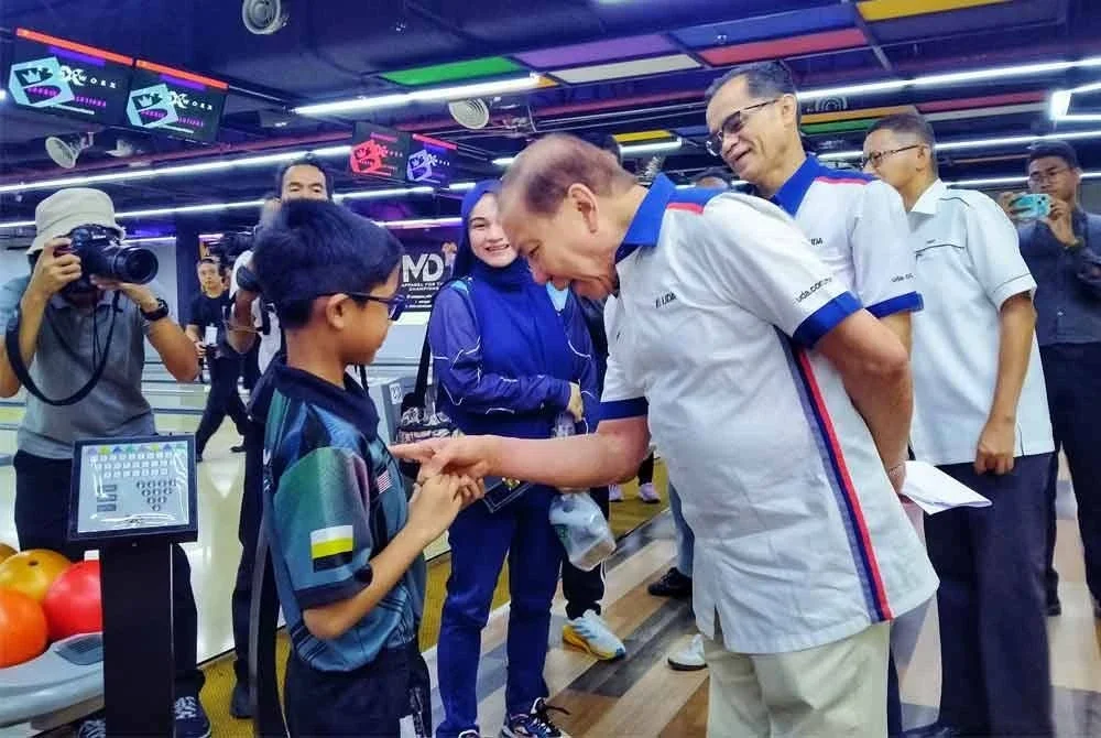 Mohd Annuar (kanan) menyantuni pelajar yang terlibat sebagai peserta sempena Majlis Perasmian Program UDA Cares: Bangunkan Komuniti, Lahirkan Juara di Lite Superbowl JB 9, Angsana Ipoh Mall di sini pada Ahad.