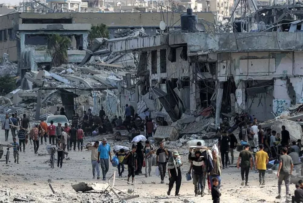 Orang ramai berjalan pulang ke kediaman di sepanjang jalan yang musnah berhampiran bangunan-bangunan yang rosak teruk di tengah bandar Khan Yunis di selatan Semenanjung Gaza selepas pengunduran pasukan Israel. (Foto AFP)