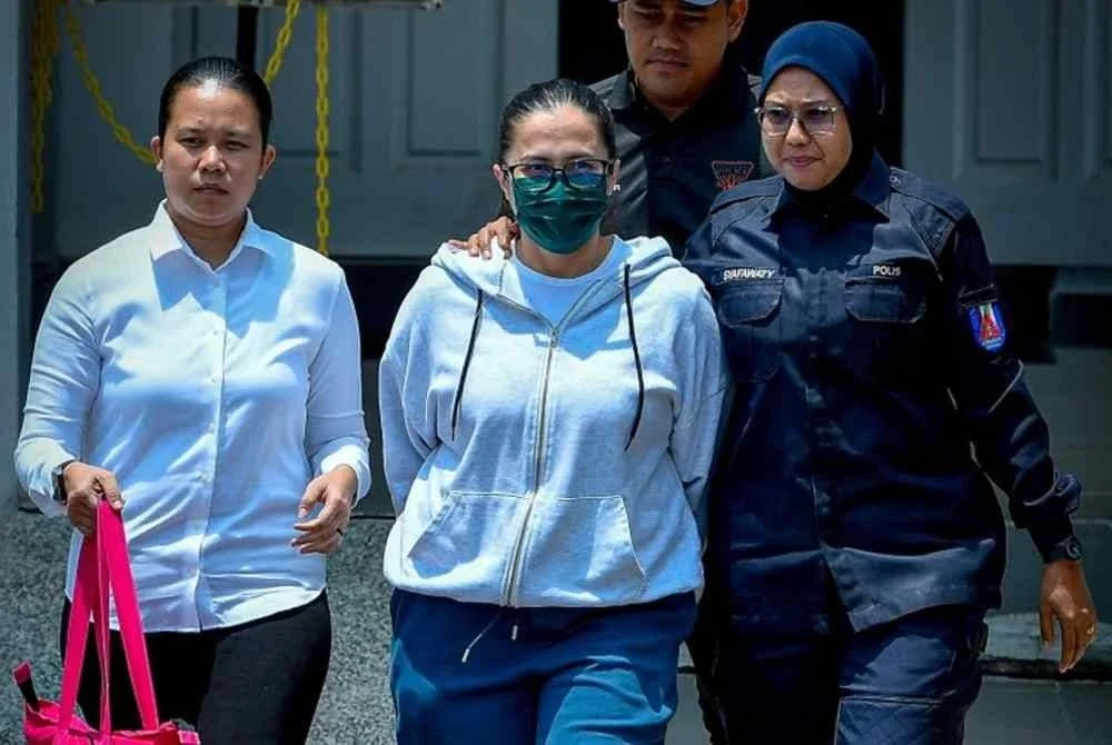 Sharifah Faraha (dua, kanan) diiringi anggota polis ketika hadir ke Mahkamah Sesyen bagi prosiding sambung perbicaraan memiliki sepucuk pistol dipercayai dibekalkan kepada warga Israel pada Isnin. Foto Bernama