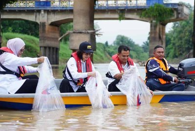 Zahari (dua dari kanan) ketika melepaskan benih udang galah di Sungai Muar pada Ahad.