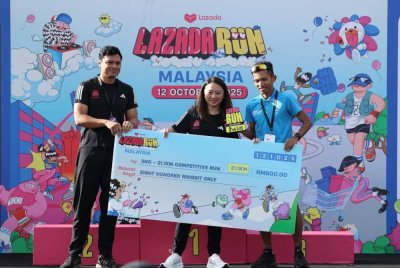 Hannah (tengah) menyampaikan hadiah kepada Edan (kanan) pada acara Lazada Run di Cyberjaya pada Ahad.