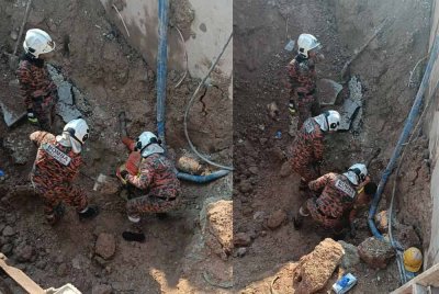 Anggota Bomba dan Penyelamat sedang mengeluarkan mangsa tertimbus akibat tanah runtuh, pada Selasa.