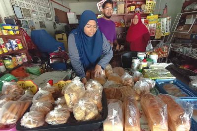 Farouq (kanan) bersama keluarganya menunjukkan roti yang dijual di kedai mereka yang beroperasi di Kampung Bukit Kubang Jambu, Kuala Terengganu.