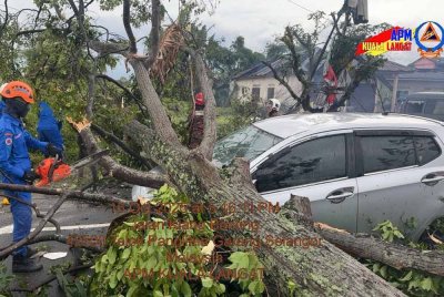 Anggota APM mengalihkan pokok tumbang menghempap sebuah kereta akibat ribut berhampiran SRA Kampung Medan, pada Rabu. Foto APM Kuala Langat