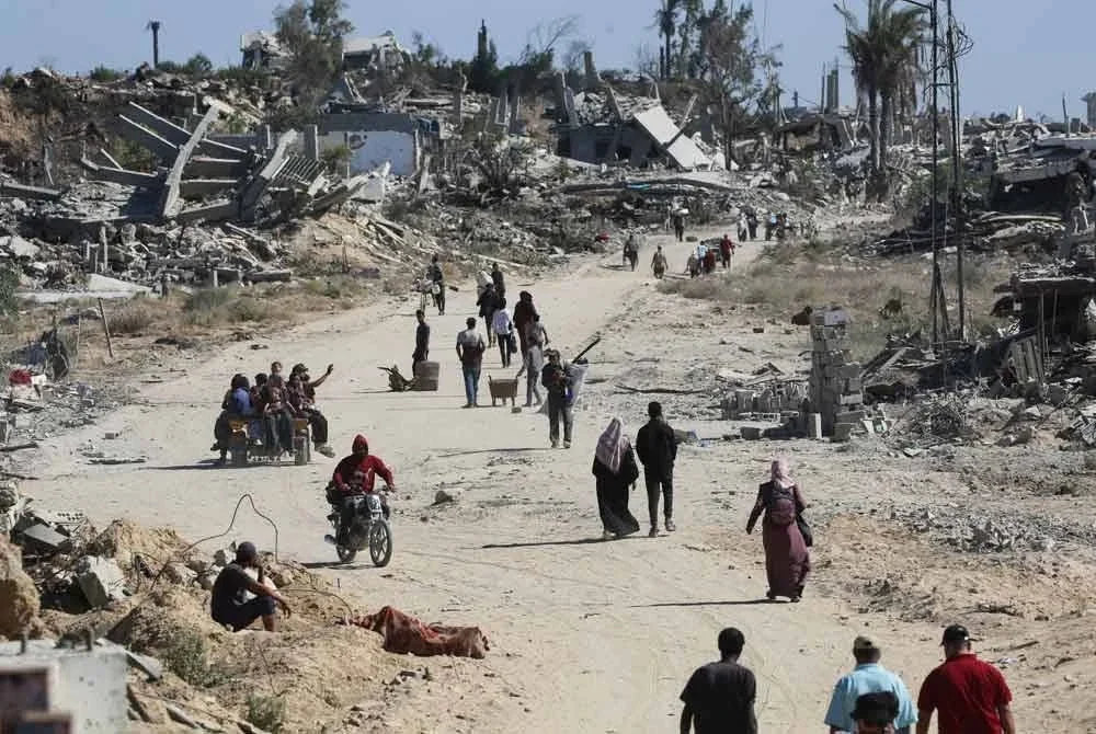 Penduduk Palestin yang kehilangan tempat tinggal berjalan melepasi bangunan musnah ketika pulang ke rumah masing-masing di kawasan al-Zahra, utara Kem Pelarian Nuseirat di Gaza Tengah.