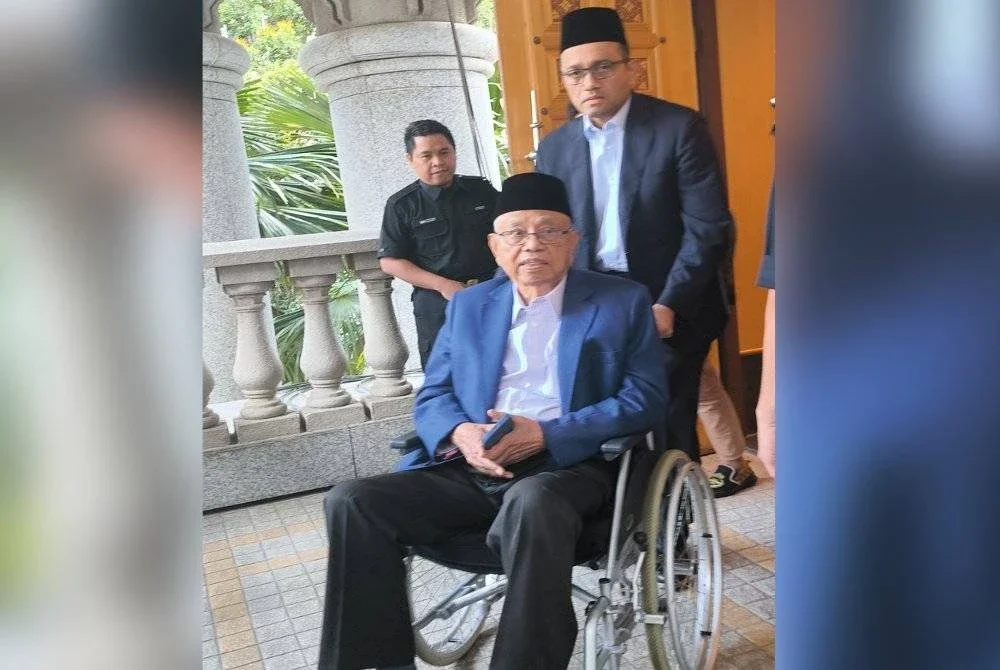 Shahriman menolak kerusi roda dinaiki Shamsuddin ketika hadir ke Mahkamah Tinggi Syariah Putrajaya pada Khamis.