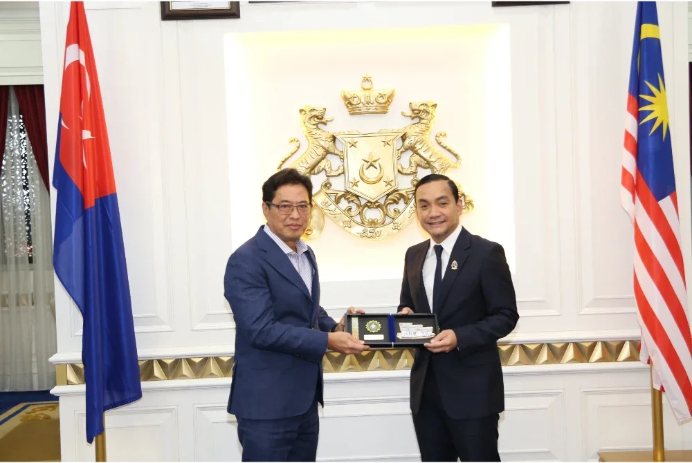 Azam (kiri) menyampaikan cenderahati kepada Onn Hafiz.