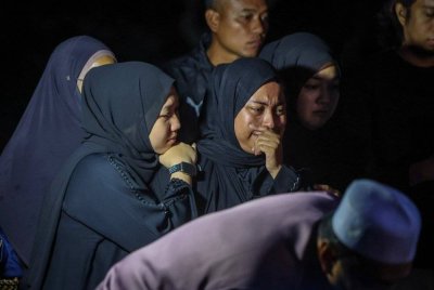 Nur Faratin (tengah) sebak ketika hadir melihat pengebumian jenazah suaminya di Tanah Perkuburan Islam Lahar Tabut pada Sabtu. Foto Bernama