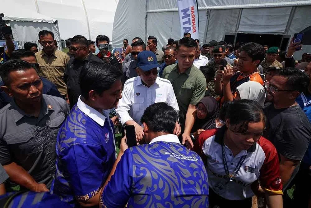 Anwar meluangkan masa menyantuni orang ramai yang hadir pada Program Madani Rakyat (PMR) 2025 di Politeknik Merlimau pada Ahad. Foto Bernama