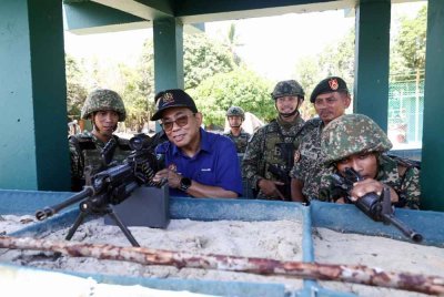 Mohamed Khaled (dua, kiri) mencuba mesingan di pos kawalan sempena lawatan kerja beliau di Pos Tanduo pada Isnin. Foto Bernama