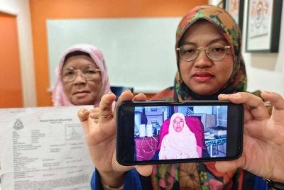 Ramlah menunjukkan gambar Roziana sambil diperhatikan oleh ibunya, Amanah.