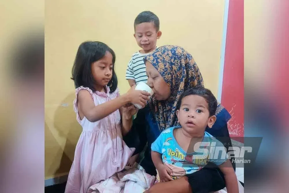 Nadlin (kiri) membantu ibunya minum semasa ditemui di rumahnya di Taman PKNK.