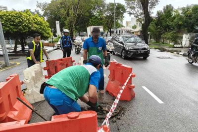 Pasukan daripada IWK dan Time membantu mengangkat serta meletakkan semula penutup ke kedudukan asal.