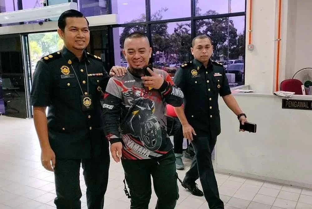 Mohammad Syafiq (tengah) diiringi pegawai KPDN ketika hadir di Mahkamah Butterworth pada Khamis.