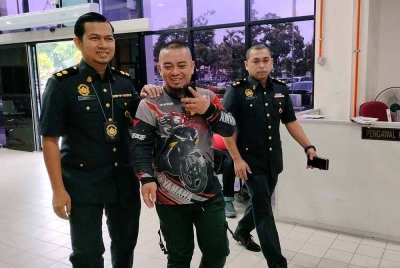 Mohammad Syafiq (tengah) diiringi pegawai KPDN ketika hadir di Mahkamah Butterworth pada Khamis.