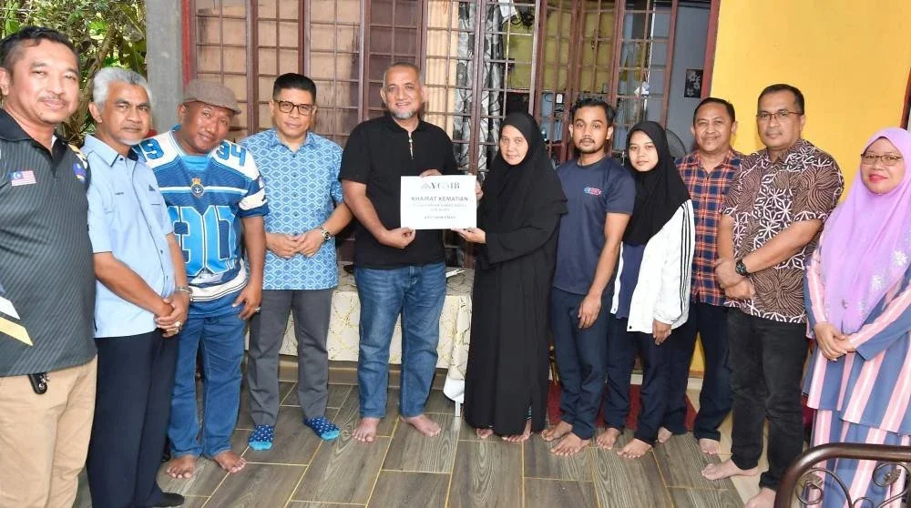 Asiah (enam dari kanan) menerima manfaat Ahli Skim Emas yang disampaikan oleh Ahli Lembaga Pemegang Amanah YGMB di rumahnya di Kampung Legeh, Jeli pada Jumaat.
