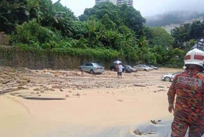 Anggota bomba melakukan pemantauan di lokasi tanah runtuh berhampiran sebuah pasar raya di kawasan Paya Terubong, Ayer Itam pada petang Jumaat.