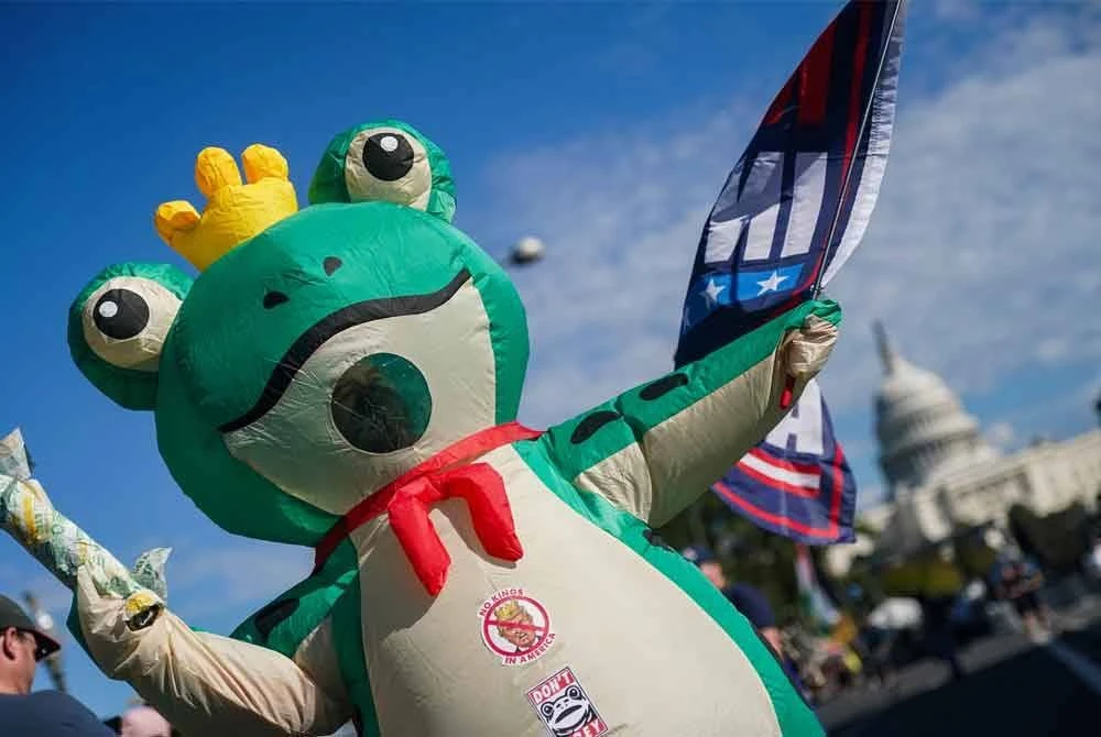 Seorang penunjuk perasaan memakai kostum katak sebagai membantah dasar keras Trump terhadap terhadap pendatang dan pelarian.