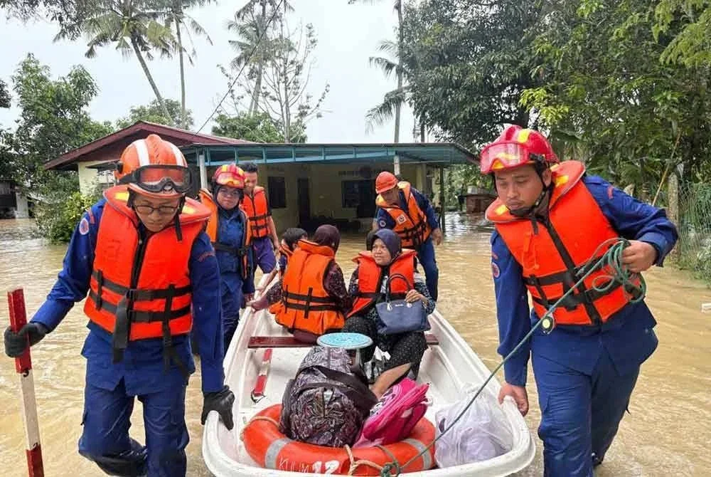 Anggota Angkatan Pertahanan Awam Malaysia (APM) memindahkan mangsa banjir ke PPS berdekatan di Pokok Sena.