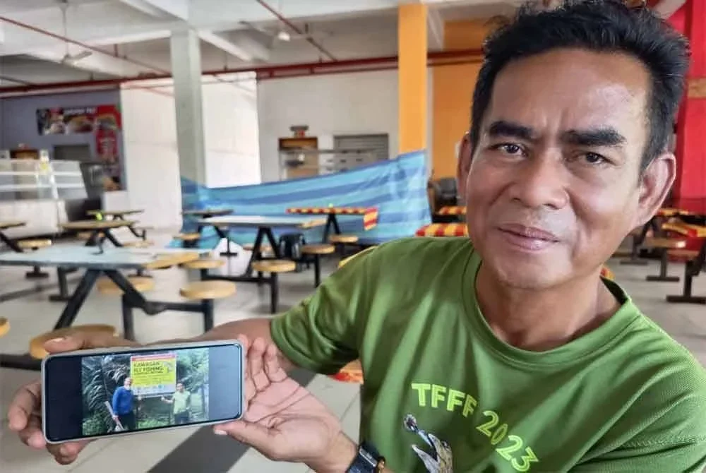 Ramli menunjukkan gambarnya bersama Christopher di hadapan papan tanda lokasi ikan sikang yang menjadi mercu tanda Kampung Betong, Hulu Terengganu.